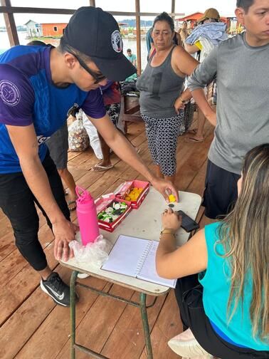 Voluntário entregando a moeda CAT para moradora da comunidade